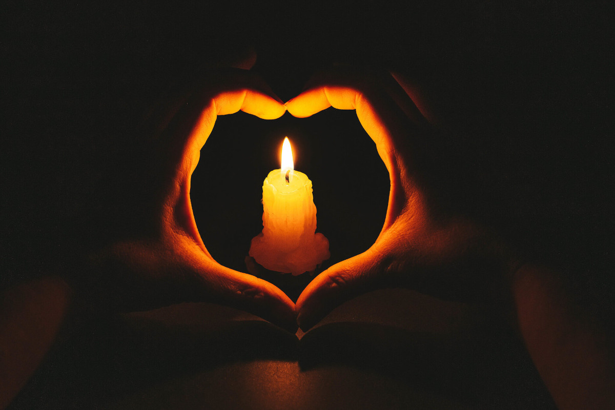 Heart-shaped hands and flame candle in darkness | Credit: Marco Verch | License: CC-BY 2.0