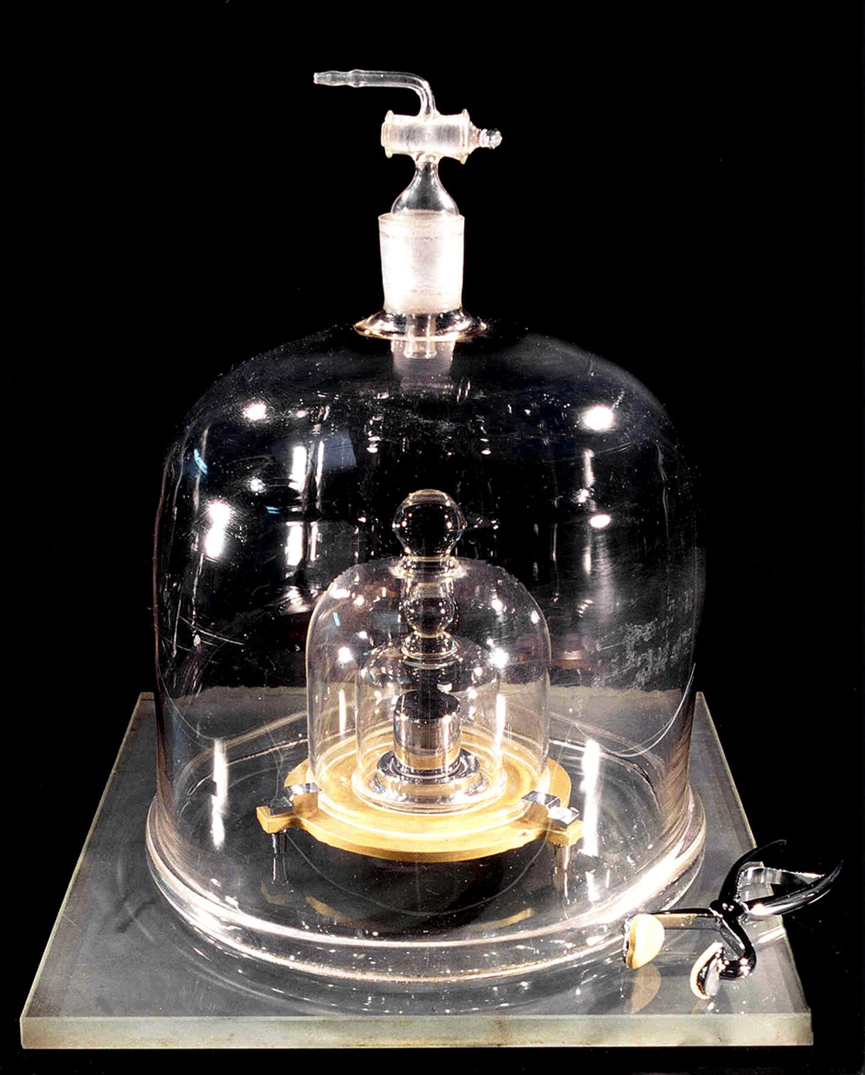 Originally, the kilogram was defined by a physical object, the cylinder pictured here, kept in a temperature and humidity-controlled vault in a series of nested bell jars. Because its mass was constantly changing over time, in 2019, the kilogram was redefined using a fundamental constant from quantum physics. | Title: International prototype of the kilogram aka Le Grand K. | Credit: BIPM | Source: NIST | License: CC BY-SA 3.0